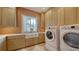 Well-equipped laundry room with modern washer, dryer, a farmhouse sink, and ample storage cabinets at 15315 Anchorage Pl, Lakewood Ranch, FL 34202
