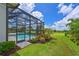 Well-manicured backyard with verdant lawn, colorful landscaping and a screened pool area at 17110 Verona Pl, Bradenton, FL 34202