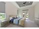 A modern bedroom with a king-size bed, gray tray ceiling, and doors that lead to the backyard at 17110 Verona Pl, Bradenton, FL 34202