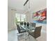 Modern dining room with a glass table, gray chairs, statement lighting, and a large colorful art piece at 17110 Verona Pl, Bradenton, FL 34202