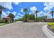 Community entrance with brick gatehouses, lush landscaping, and palm trees under a sunny blue sky at 17110 Verona Pl, Bradenton, FL 34202