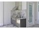 Outdoor kitchen with stainless steel grill, marble backsplash, and gray cabinets for elegant outdoor cooking at 17110 Verona Pl, Bradenton, FL 34202