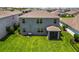 Back aerial view of a house with a large backyard, neutral color palette, and screened patio at 17209 Barnwood Pl, Bradenton, FL 34211