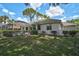 Backyard view of a well-maintained lawn, manicured bushes, and a screened-in pool and patio area, with clear blue skies at 2016 White Feather Ln, Nokomis, FL 34275