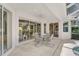 Covered patio with a ceiling fan and dining table looking into an open living space through large glass sliding doors at 2016 White Feather Ln, Nokomis, FL 34275