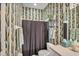 Full bathroom with decorative wall paper, shower with curtains and chrome shelving at 2025 Lynx Run, North Port, FL 34288