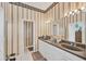 Elegant bathroom featuring a double vanity, neutral color palette, and decorative wallpaper at 2025 Lynx Run, North Port, FL 34288