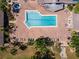 Community pool with brick patio, shuffleboard courts, manicured lawn, mature trees, and inviting lounge area at 204 Aspen St, Englewood, FL 34223