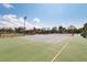 Outdoor tennis court surrounded by trees and landscaping, with covered seating area at 204 Aspen St, Englewood, FL 34223