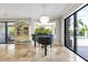 Bright dining area features a piano, glass display case, chandelier, and sliding glass doors to the outdoor pool at 21210 77Th E Ave, Bradenton, FL 34202