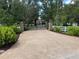 Paver driveway with gated entrance, mature trees, and lush landscaping leading to a luxurious home at 21210 77Th E Ave, Bradenton, FL 34202