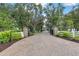 Paver driveway with gated entrance, mature trees, and lush landscaping leading to a luxurious home at 21210 77Th E Ave, Bradenton, FL 34202