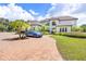 Estate home with mature palm trees, a circular driveway, and a blue sports car in front at 21210 77Th E Ave, Bradenton, FL 34202