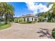 Garage exterior view with lush landscaping, a circular driveway, and picturesque pond in the backdrop at 21210 77Th E Ave, Bradenton, FL 34202