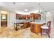 Open kitchen with custom cabinetry, stainless appliances, island with seating, and travertine floors at 21210 77Th E Ave, Bradenton, FL 34202