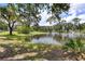 Scenic view of a pond with fountain, lush landscaping, and glimpses of the home in the background at 21210 77Th E Ave, Bradenton, FL 34202