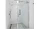 Modern bathroom featuring a glass-enclosed shower with pebble flooring and textured white tile walls at 2155 Harbourside Dr # 804, Longboat Key, FL 34228