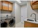 Bright laundry room featuring modern washer and dryer units, storage cabinets, and a utility sink with quartz countertops at 2761 Feiffer Cir, Sarasota, FL 34235