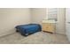 Neutral carpeted bedroom featuring a bed with blue blanket, a desk, and a window at 2920 Oriole Dr, Sarasota, FL 34243