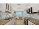 Bright kitchen features white cabinets, granite countertops, stainless steel appliances, and beautiful waterfront view at 350 Golden Gate Pt # 61, Sarasota, FL 34236
