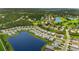 A high-angle aerial shot displays a residential area next to a lake, surrounded by lush greenery at 3621 Wild Blossom Pl, Parrish, FL 34219