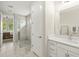 Bright bathroom featuring a walk-in shower with marble tile and white cabinets with marble countertops at 3621 Wild Blossom Pl, Parrish, FL 34219