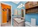 Bathroom showcasing a single sink vanity, toilet, built in storage, a bright blue wall and a shower with a showerhead at 4145 W Price Blvd, North Port, FL 34286