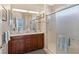 Bright bathroom featuring double sink vanity with wood cabinets and glass enclosed shower at 4200 Reflections Pkwy, Sarasota, FL 34233