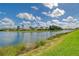 Picturesque lake view with lush green grass, scattered clouds, and beautiful neighborhood at 4200 Reflections Pkwy, Sarasota, FL 34233