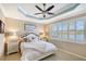 Inviting main bedroom featuring a decorative tray ceiling, comfortable furnishings, and bright windows with shutters at 4200 Reflections Pkwy, Sarasota, FL 34233