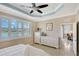 Spacious main bedroom with a tray ceiling, white furniture, and a large window overlooking the serene lake at 4200 Reflections Pkwy, Sarasota, FL 34233