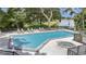 Community pool and hot tub with lounge chairs, lush trees, and a view of the lake at 4333 Trails Dr # 10-1, Sarasota, FL 34232
