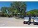 Golf carts parked in front of a building with mature trees in a parking lot on a sunny day at 4374 Mirabella Cir, Bradenton, FL 34210