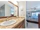 Bathroom boasts a vanity with a granite countertop, large mirror, and doorway view into bedroom at 5417 Champagne # 63, Sarasota, FL 34235
