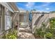 Charming courtyard entrance with a metal gate, lush greenery, and a brick paver walkway at 5417 Champagne # 63, Sarasota, FL 34235