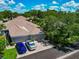 Exterior view featuring garages, lush landscaping, and a brick paver driveway beneath a bright, partly cloudy sky at 5417 Champagne # 63, Sarasota, FL 34235