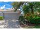 Attached garage with a gray door, brick paver driveway, and lush tropical landscaping at 5417 Champagne # 63, Sarasota, FL 34235