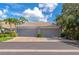 Attached garages with gray doors and a brick paver driveway beneath a sunny, partly cloudy sky at 5417 Champagne # 63, Sarasota, FL 34235
