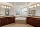 En-suite bathroom featuring granite countertops, double vanity, jacuzzi soaking tub, and plantation shutters at 584 Mast Dr, Bradenton, FL 34208