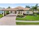 Beautiful home exterior with lush landscaping, portico, and brick driveway at 584 Mast Dr, Bradenton, FL 34208