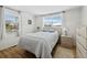A bright bedroom has multiple windows with white curtains, wood floors, and neutral-tone furniture at 663 Penfield St, Longboat Key, FL 34228