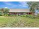 Exterior view of the back of the barn-style home with a screened in porch and spacious lawn at 6633 Old Ranch Rd, Sarasota, FL 34241