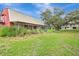 Spacious backyard with tall grasses, chain link dog run, and covered patio attached to the barn-style home at 6633 Old Ranch Rd, Sarasota, FL 34241