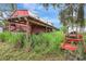View of the red barn with rustic wooden porch and overgrown foliage at 6633 Old Ranch Rd, Sarasota, FL 34241