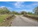 Estate home featuring stone wall details and a long driveway, surrounded by lush landscaping at 6633 Old Ranch Rd, Sarasota, FL 34241