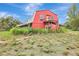 Two-story red barn-style home featuring a small balcony overlooking the partially mowed expansive lawn at 6633 Old Ranch Rd, Sarasota, FL 34241