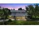 Two-story home with stone facade, covered porch, well-manicured lawn, and mature trees at twilight at 6633 Old Ranch Rd, Sarasota, FL 34241
