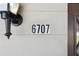 Close-up of the house number '6707' displayed on the exterior wall near a charming outdoor light fixture at 6707 Northampton Pl, Bradenton, FL 34207