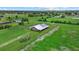 Aerial view of metal building set on spacious green lawns and pastures, fenced in for livestock at 6805 225Th E St, Bradenton, FL 34211
