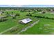 Aerial view of fenced barn with metal roof, located on a sprawling green property with ponds and mature trees at 6805 225Th E St, Bradenton, FL 34211